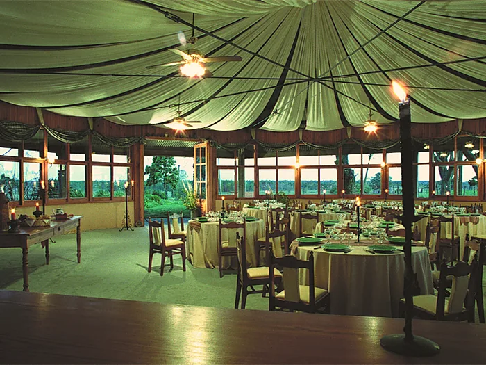 Interior del salón con las mesas redondas servidas y el techo entelado.