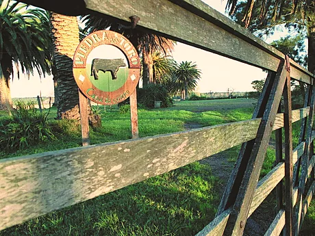 El cartel de entrada de Piedra del Toro sobre la tranquera.